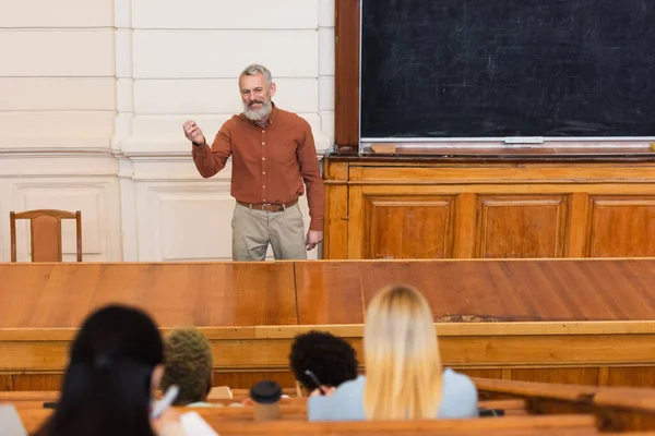 Smiling Professor Talking Lecture Blurred Interracial Students University — Stock Photo, Image