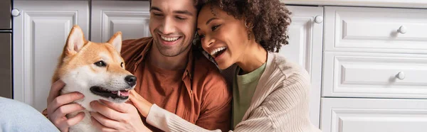 Joyful Interracial Couple Embracing Shiba Inu Dog Home Banner — Stock Photo, Image