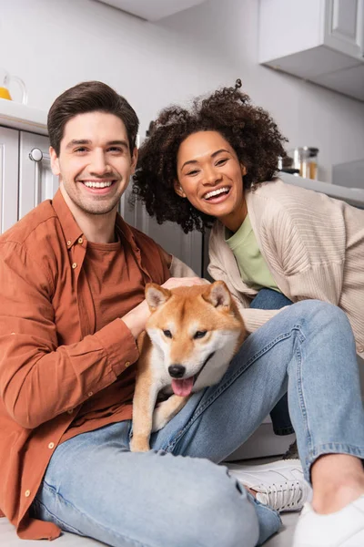 一对快乐的跨种族夫妇在滑稽的狗儿旁边看着相机 — 图库照片