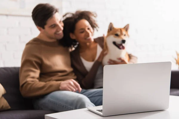Laptop Soffbord Nära Suddig Multietniskt Par Med Shiba Inu Hund — Stockfoto