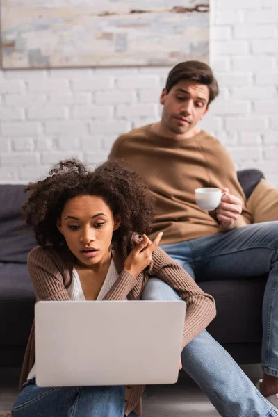 African American Freelancer Laptop Pointing Finger Blurred Boyfriend Coffee Home — Stock Photo, Image