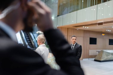 Afrika kökenli Amerikalı koruma. Bulanık ön planda, iki ırklı güvenliğin yanındaki otelde üst düzey bir iş kadınını koruyor.
