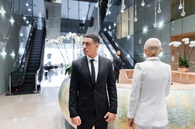 Yetişkin iş kadını, ırklar arası korumaların yakınındaki otel resepsiyonunda.