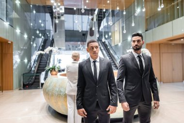 Otel resepsiyonunda duran olgun iş kadınlarını koruyan çok ırklı korumalar.