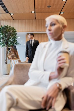 selective focus of african american bodyguard near senior business lady on blurred foreground clipart