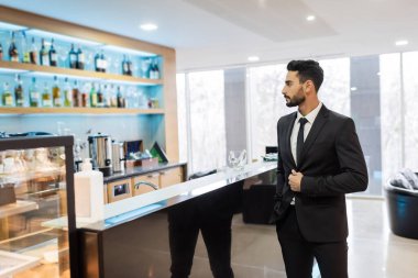 Otel lobisinde barın yanında duran melez bir güvenlik görevlisi.
