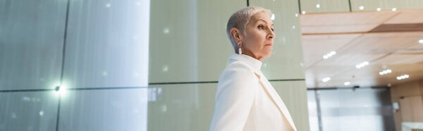 side view of fashionable senior business lady in hotel lobby, banner