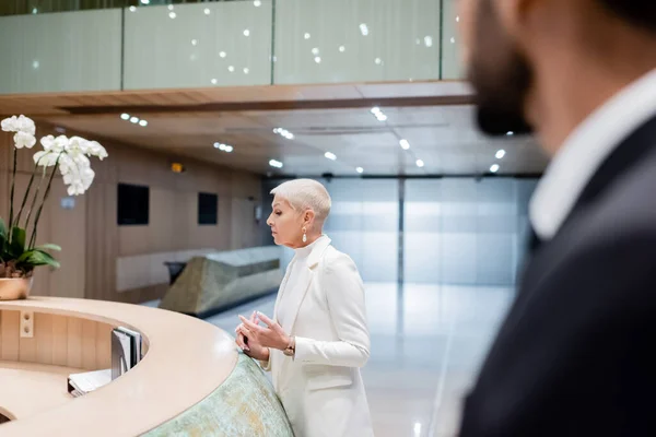 Trendy Senior Businesswoman Hotel Reception Racial Bodyguard Sturred Foreground — Stock fotografie