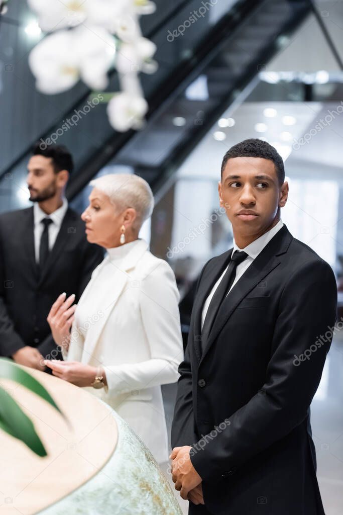 multiethnic bodyguards protecting mature businesswoman checking in at hotel reception