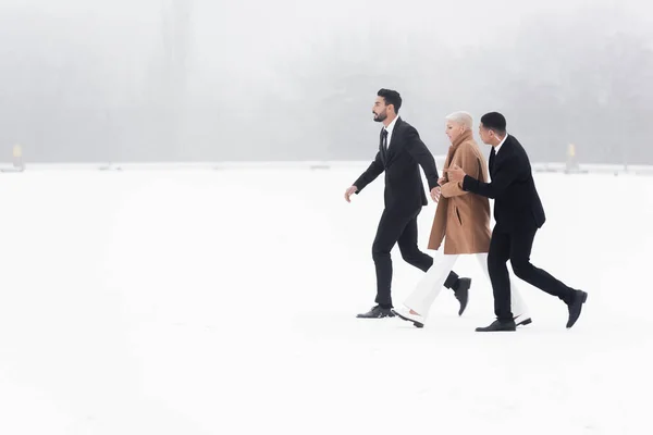 Side View Senior Businesswoman Walking Snowy Field Protection Interracial Bodyguards — Stock Photo, Image