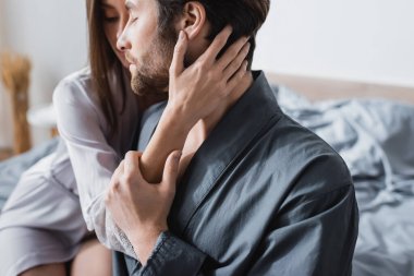 İpek bornozlu şehvetli bir kadın. Gözleri kapalı, sakallı sevgilisine sarılıyor. 