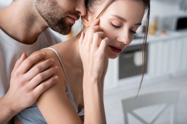 Sakallı adam evde genç ve güzel bir kadına sarılıyor.