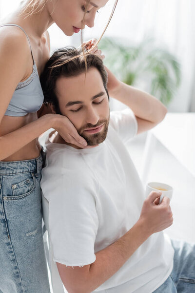 красивая женщина в шелковом лифчике обнимает парня с чашкой 