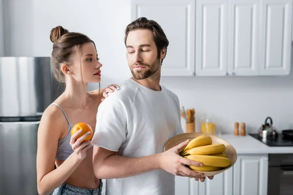 Junge Frau Hält Orangefarbenen Mann Mit Bananen — Stockfoto