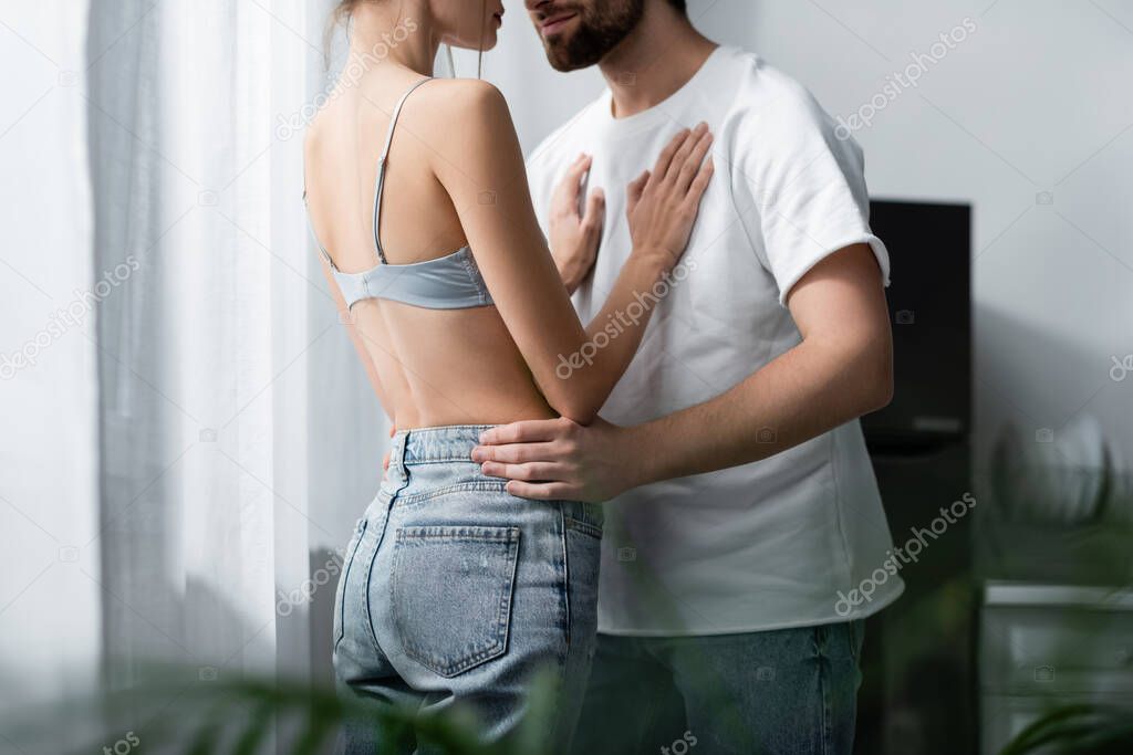 cropped view of woman in bra and bearded man hugging at home