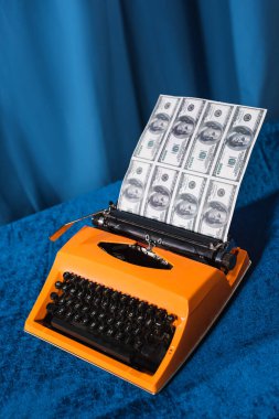 vintage typewriter and dollar banknotes on velour tablecloth and blue background clipart