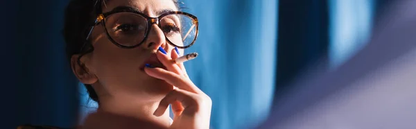 穿着老式眼镜的时髦女人在蓝色背景 横幅上抽烟 — 图库照片