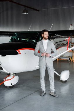 Helikopterin yanında ceketini ilikleyen takım elbiseli sakallı bir işadamı. 