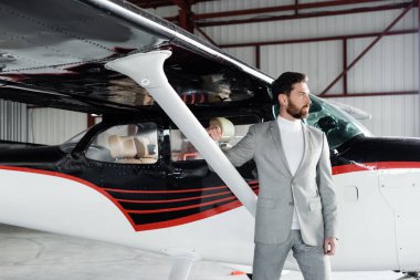 Modern helikopterin yanında duran kendine güvenen sakallı iş adamı.