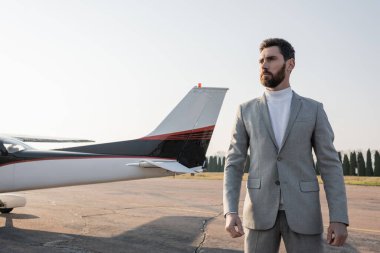 Takım elbiseli ciddi bir işadamı helikopterin yanında duruyor. 