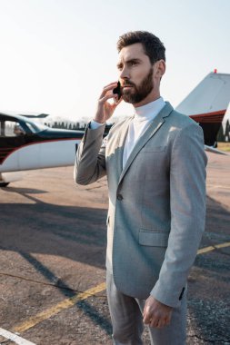 Sakallı iş adamı, helikopterin yakınındaki akıllı telefondan arıyor. 