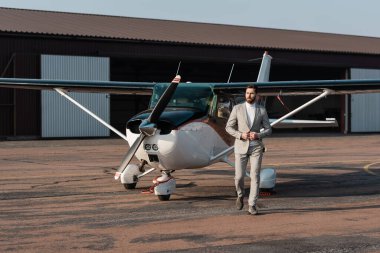 Modern helikopterin yanında yürüyen takım elbiseli sakallı bir işadamı. 
