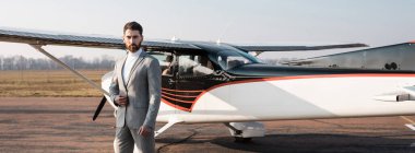Modern helikopterin yanında duran başarılı iş adamı blazer ceket ve afişi ayarlıyor.