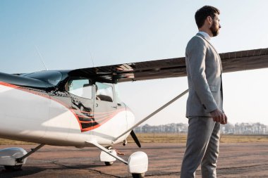Dışarıda helikopterin yanında duran takım elbiseli başarılı iş adamının yan görüntüsü. 