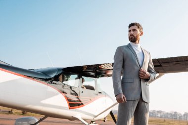 Açık havada helikopterin yanında duran takım elbiseli başarılı iş adamının düşük açılı görüntüsü 