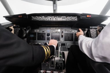 Uçak simülatöründe boyunduruk ve itme kolu kullanan pilotların kırpılmış görüntüsü 