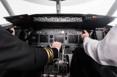 cropped view of pilots using yoke and thrust lever in airplane simulator  clipart