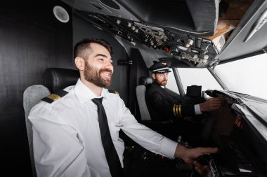 Kaptan yakınında boyunduruk kullanan neşeli yardımcı pilot uçak simülatöründe kontrol paneline ulaşıyor. 