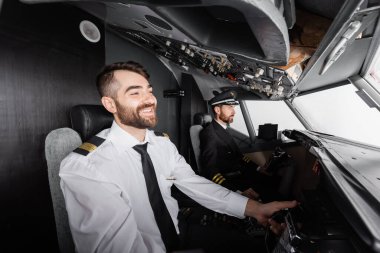 smiling co-pilot using yoke near captain while piloting in airplane simulator  clipart