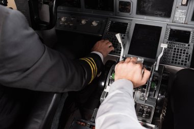 high angle view of co-pilot using thrust lever near captain in airplane simulator clipart