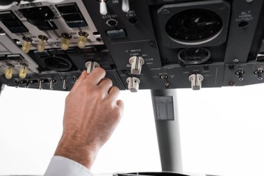 Pilotun uçak simülatörünün tepe panelinde anahtar kullanmasının kırpılmış görüntüsü 