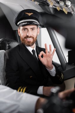 Üniformalı sakallı pilot iyi ve bulanık yardımcı pilotun yanında gülümsüyor. 