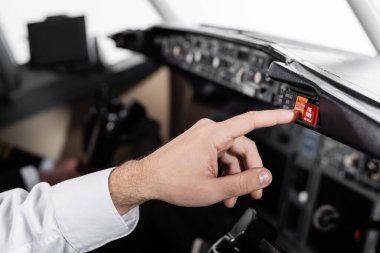 Uçak simülatöründe pilot ana uyarı düğmesine basarken kırpılmış görünüm 