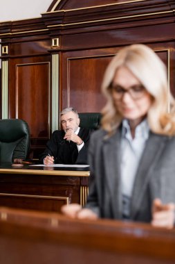senior grey-haired judge looking at advocate on blurred foreground clipart
