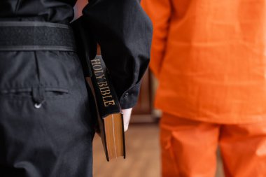 Mahkemede sanığın yanında dururken İncil 'i tutan kırpılmış mübaşirin arka görünüşü