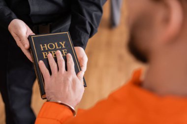 partial view of accused man giving swear on bible near bailiff in court clipart