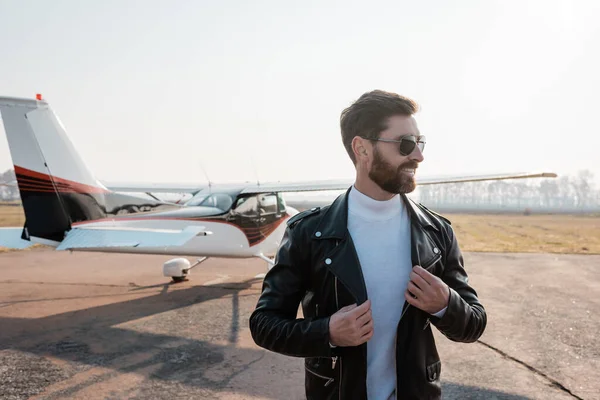 Piloto Feliz Gafas Sol Ajustando Elegante Chaqueta Cuero Cerca Helicóptero —  Fotos de Stock