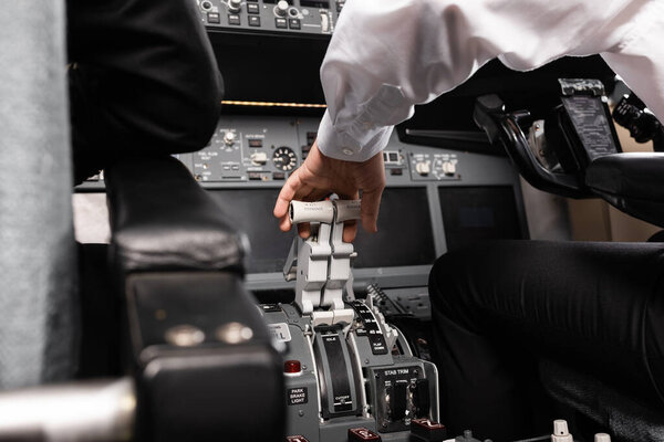 cropped view of co-pilot using thrust lever in airplane simulator