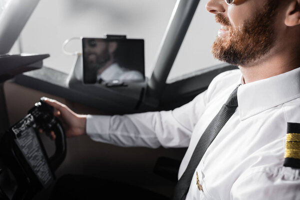 обрезанный вид веселый пилот в форме со значком с помощью ярма