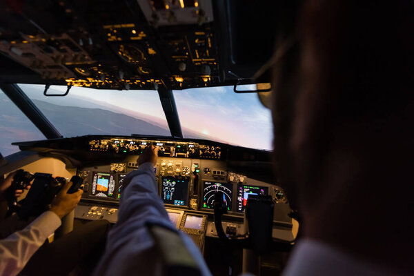 back view of professionals piloting airplane simulator in evening 