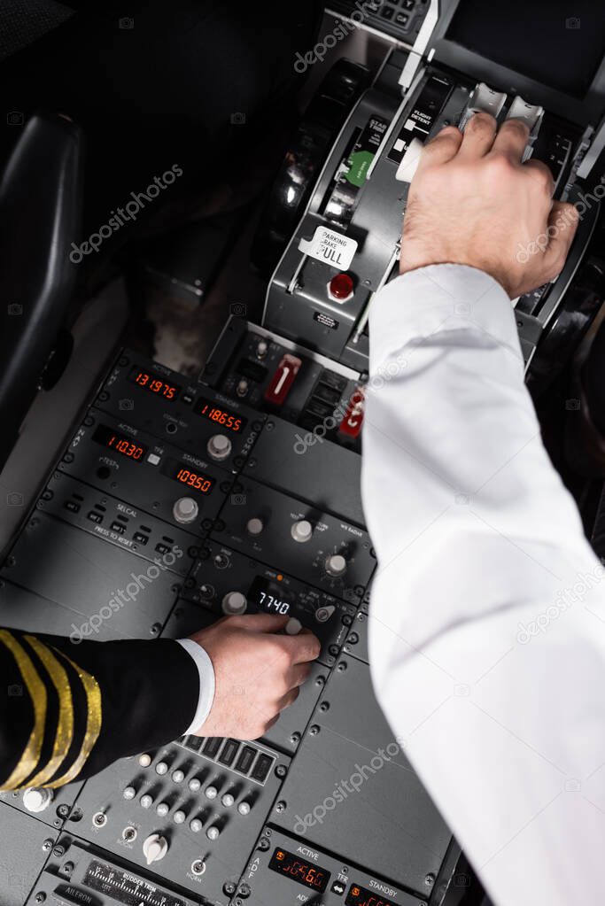 top view of pilots using control panel and thrust lever in airplane 
