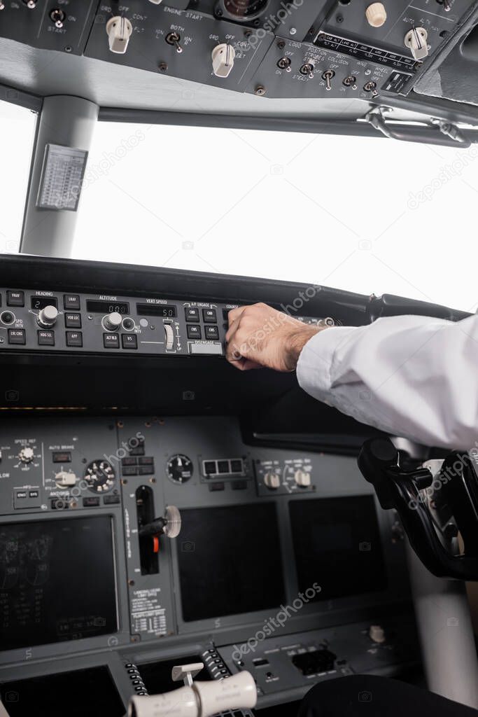 cropped view of pilot reaching control panel in airplane
