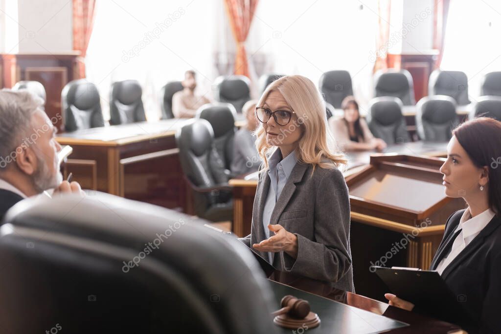 attorney pointing with hand while talking to judge near prosecutor during litigation