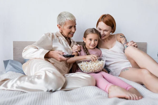 Sorridente Ragazza Che Tiene Popcorn Mentre Guarda Vicino Lesbiche Mamme — Foto Stock