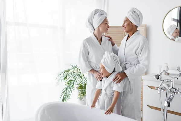 Smiling Lesbian Couple Standing Adopted Daughter Bathrobe Bathtub Home — Stock Photo, Image