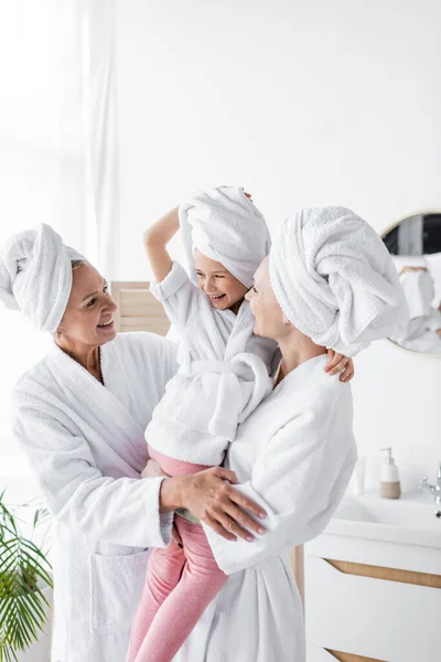快乐的女同性恋夫妇把女儿抱在毛巾里 把浴衣放在浴室里 — 图库照片